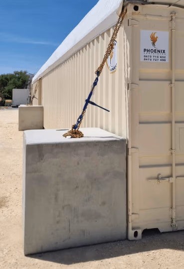 Heavy-duty chain and concrete block securing a Phoenix container tent for structural stability